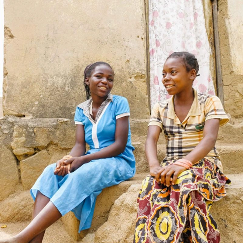 Deux filles en République centrafricaine sont assises devant un immeuble.
