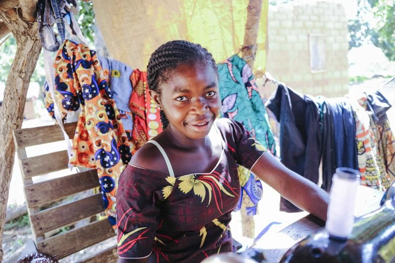 Une femme centrafricaine est assise devant une machine à coudre.
