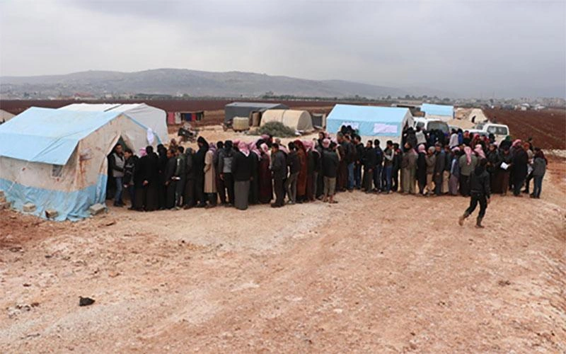 En Syrie, une longue file de parents attend devant une tente pour recevoir des vêtements d'hiver pour leurs enfants.