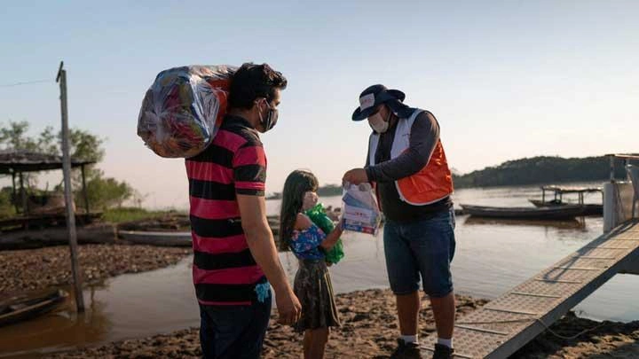 Un employé de World Vision remet une trousse alimentaire à une fillette.