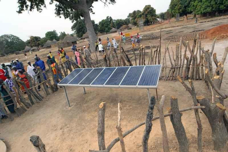 Un panneau solaire entouré d’une clôture en bois se dresse au cœur d’une communauté au Sénégal.
