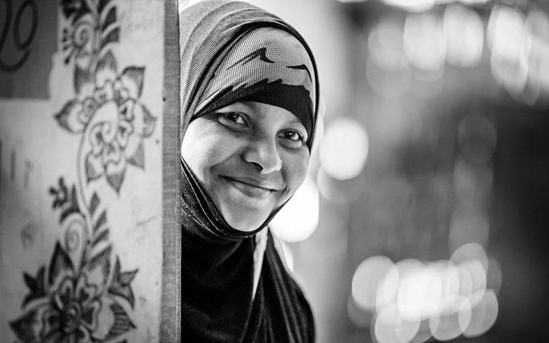 Un portrait en noir et blanc d'une femme souriante, la tête couverte.