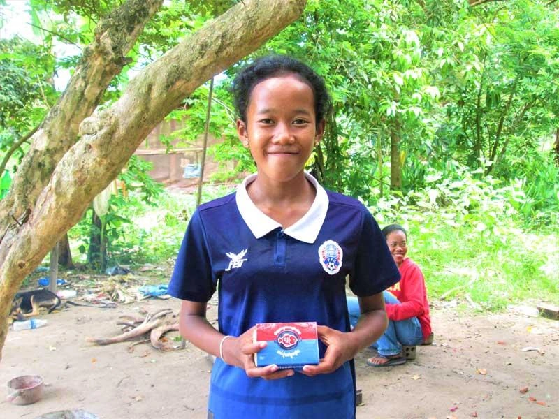 Une fillette cambodgienne tient dans ses mains une petite boîte contenant le « Lucky Iron Fish ».