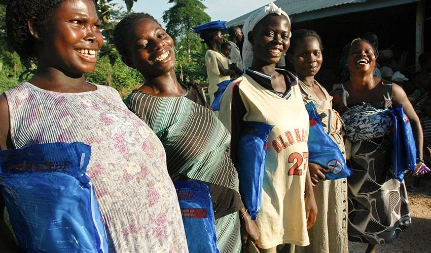 Un groupe de mères fait la file, tenant à la main des nouvelles moustiquaires qui les protégeront, elles et leurs bébés, contre le paludisme et d’autres maladies transmises par les maringouins.