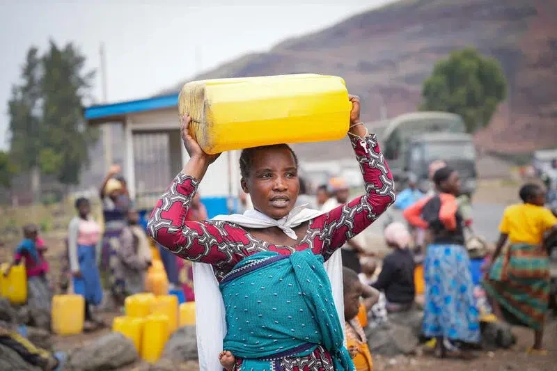 Une femme porte une cruche d'eau sur la tête.