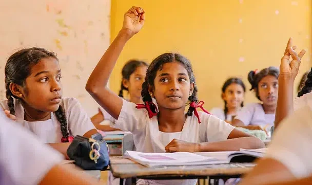 Une écolière aux deux tresses lève la main pour répondre à une question. (Sri Lanka, 2025)