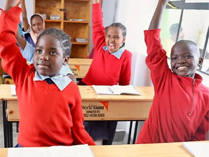 Students in a class raising their hands up.