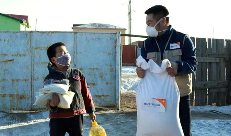 Man and boy carry World Vision supplies.