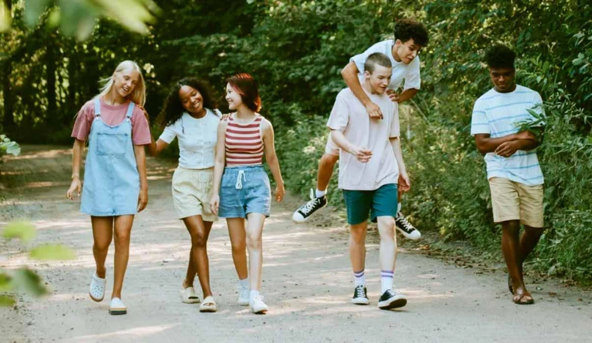Six youth from North America walk down a dusty rural road.