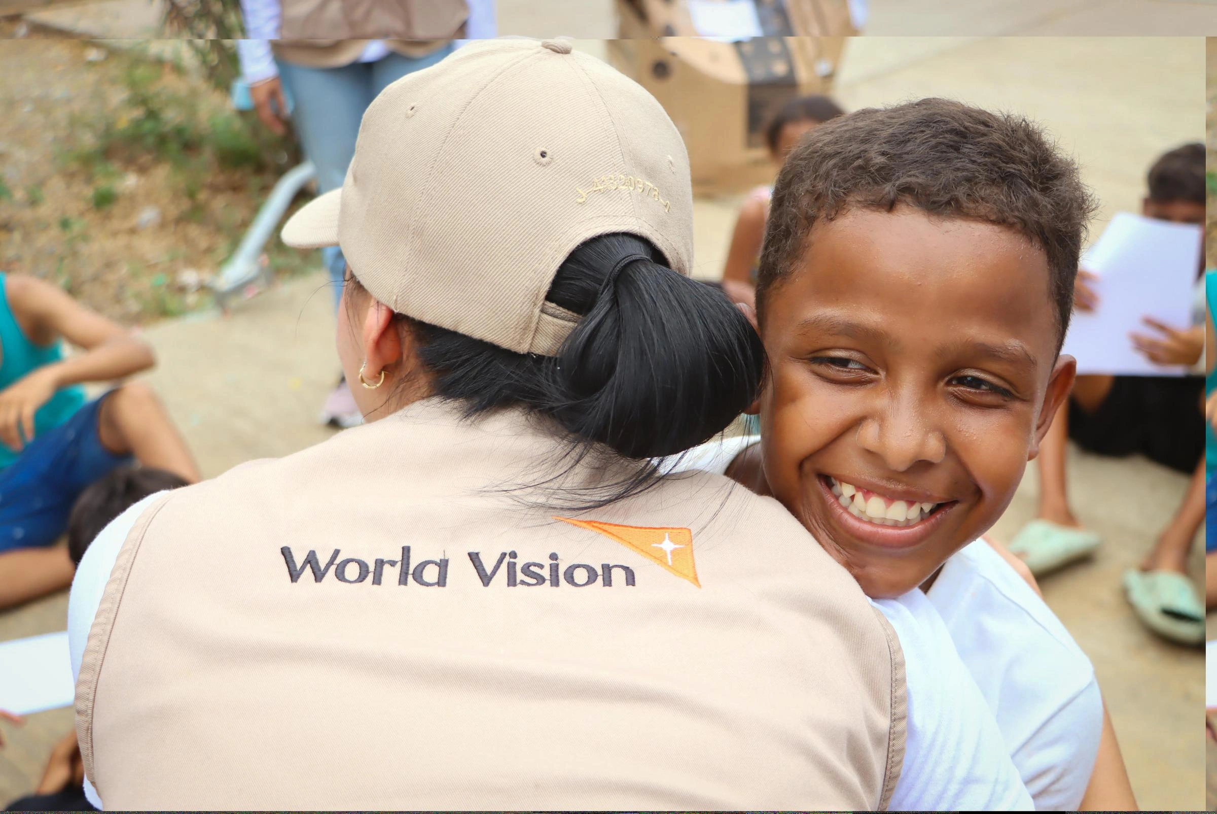 A young boy smiles as he hugs a World Vision volunteer during humanitarian operations in Venezuela.