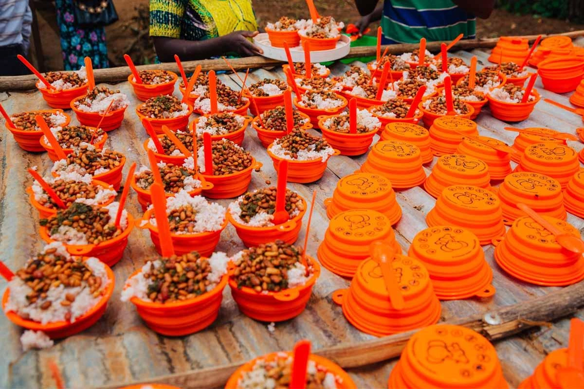 Many orange bowl and spoon sets provided by World Vision placed on a makeshift table.
