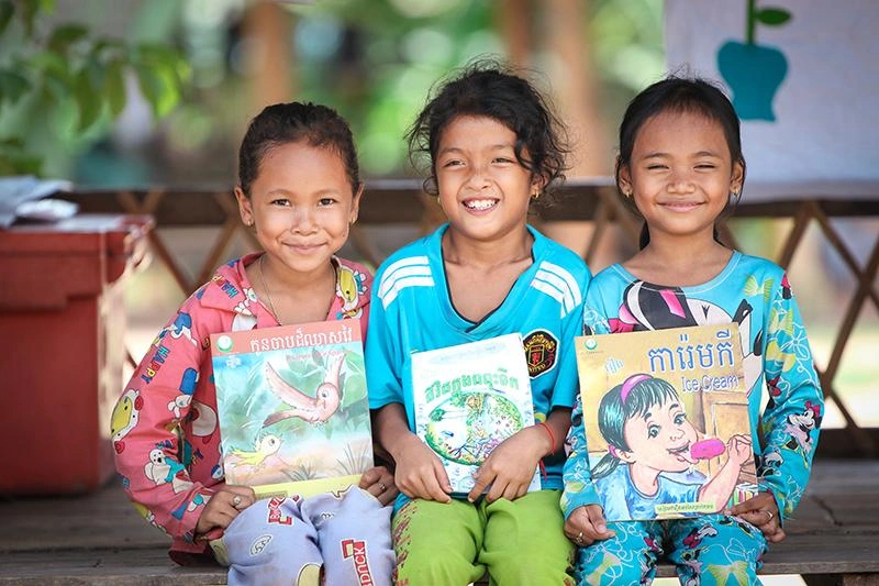 Three girls smiling with book
