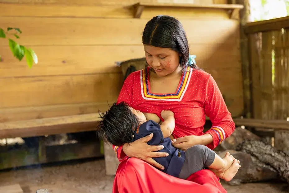 A young mother cuddles her baby as she breastfeeds.