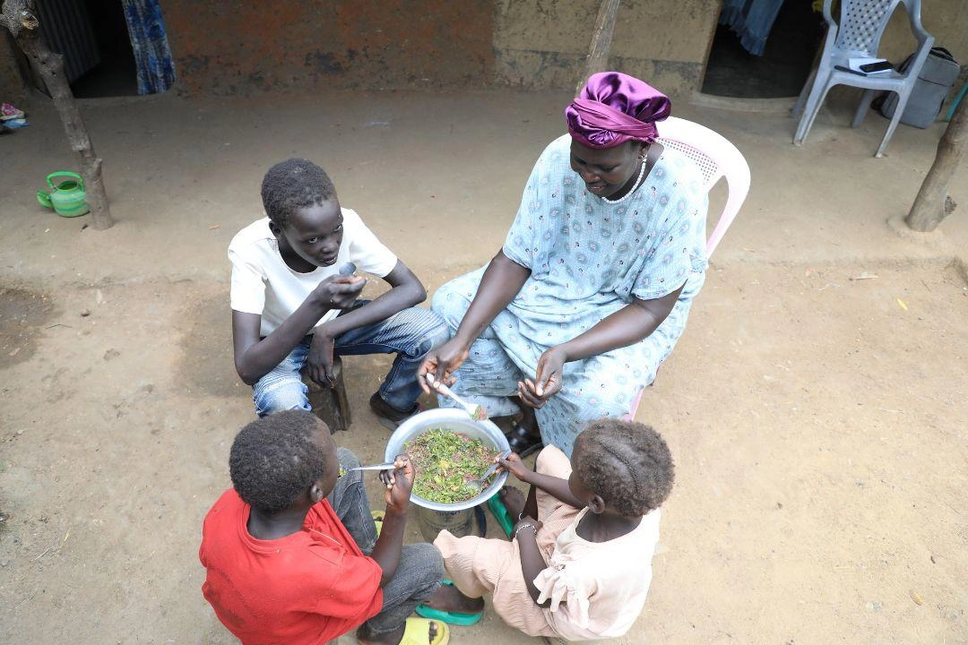 A family of four sits together to eat dinner.