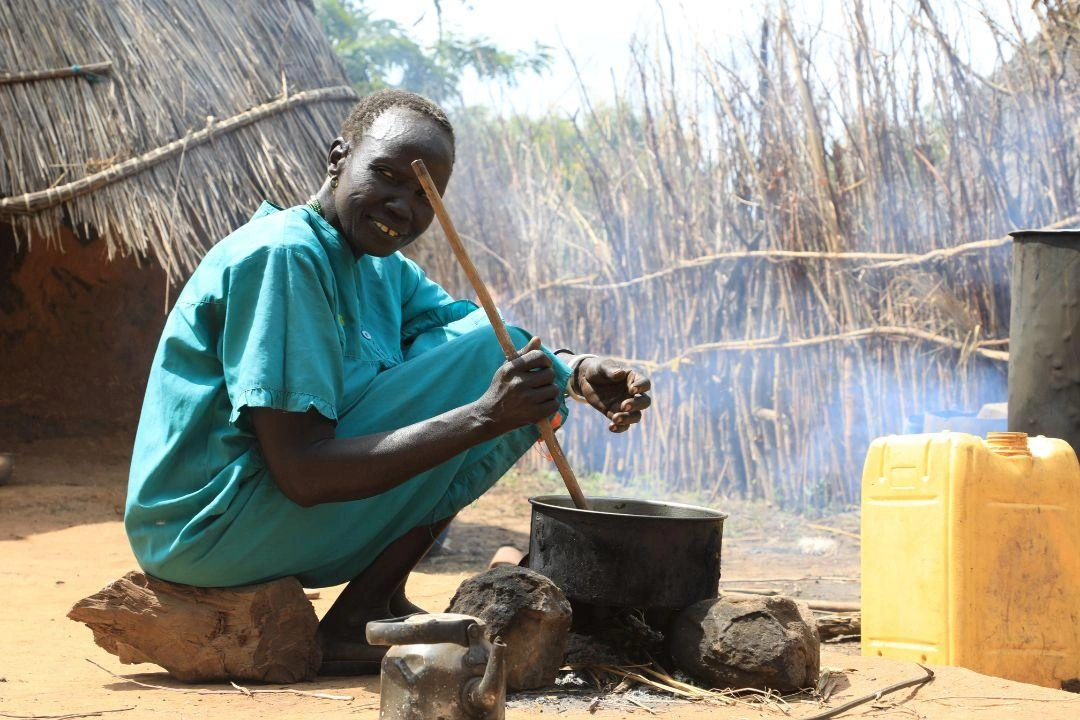 A grandmother makes food over a fire with food items she received through partnership with World Vision and World Food Programme.