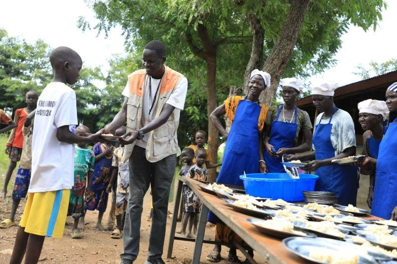 Gatwech a fait la file au point de distribution de repas de l'école pour recevoir un repas remis par un employé de World Vision.