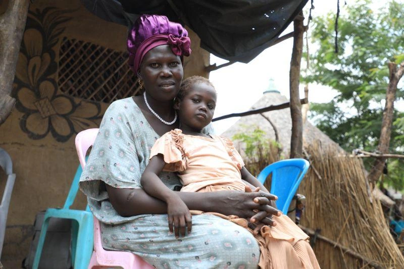 A mother sits with her young daughter.