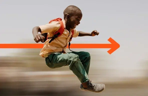 A joyful boy jumping in the air with an orange arrow behind him symbolizing forward change.