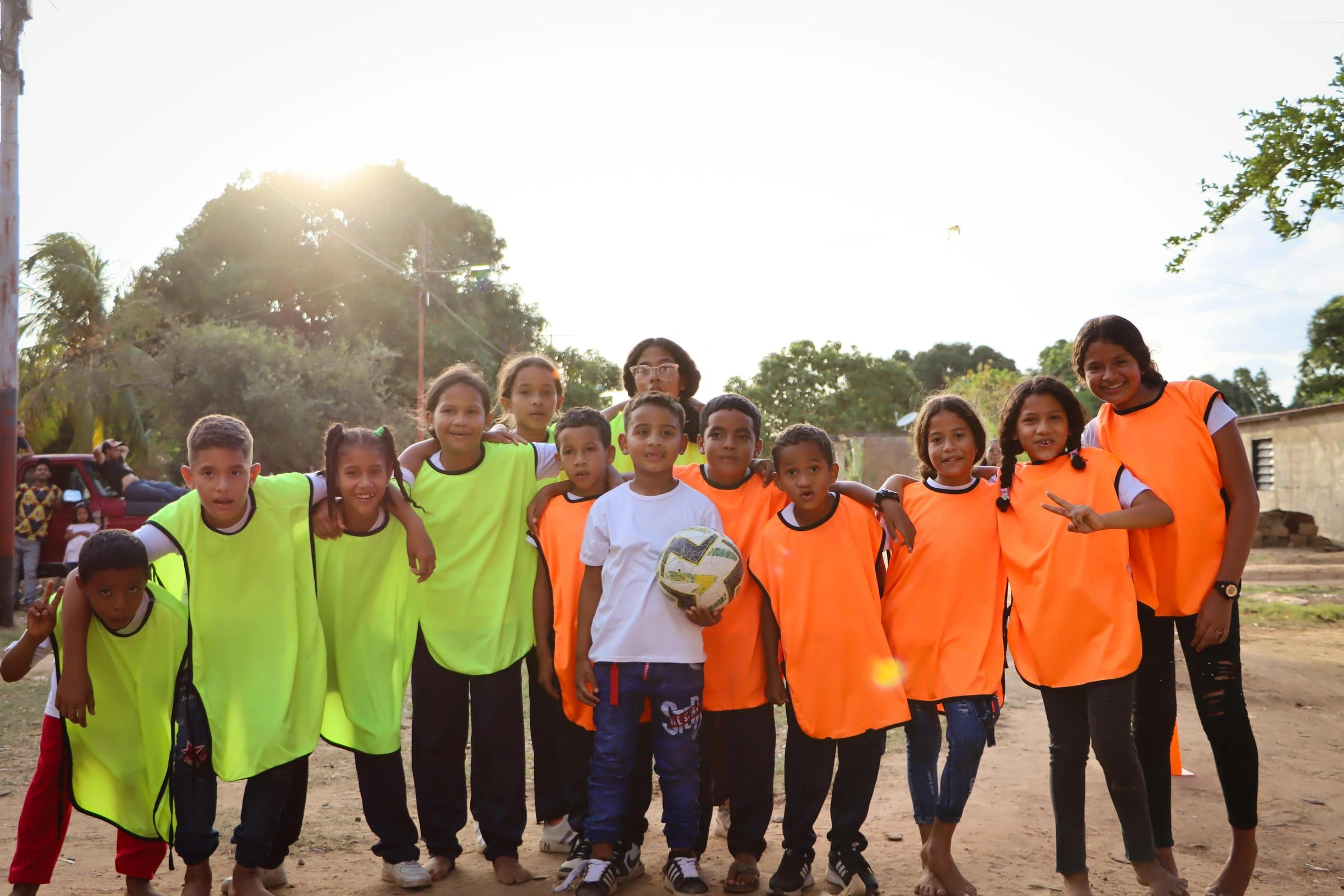 A group of kids hold a soccer ball and smile.