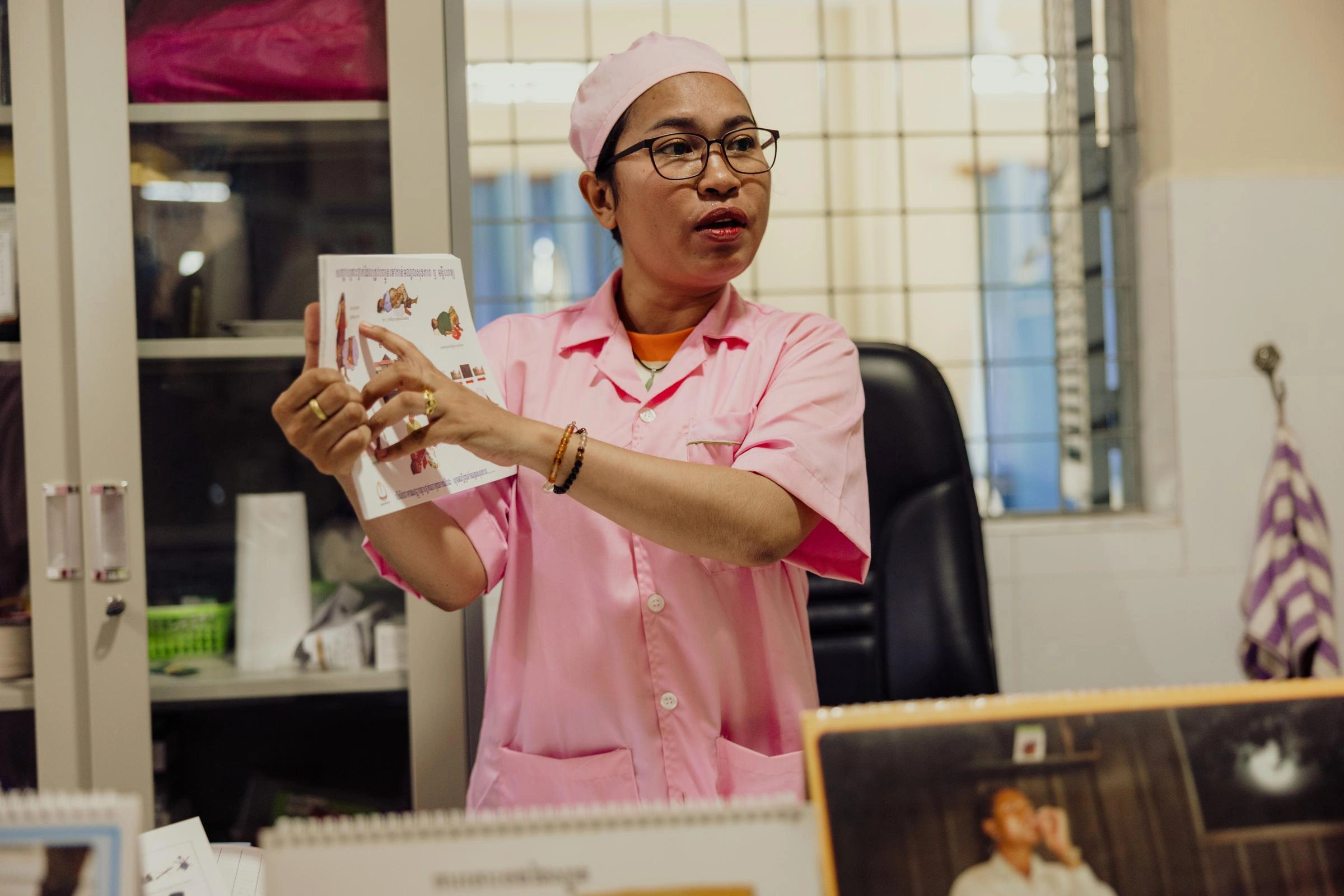 A midwife in pink scrubs points to a sheet of paper with information about childbirth.