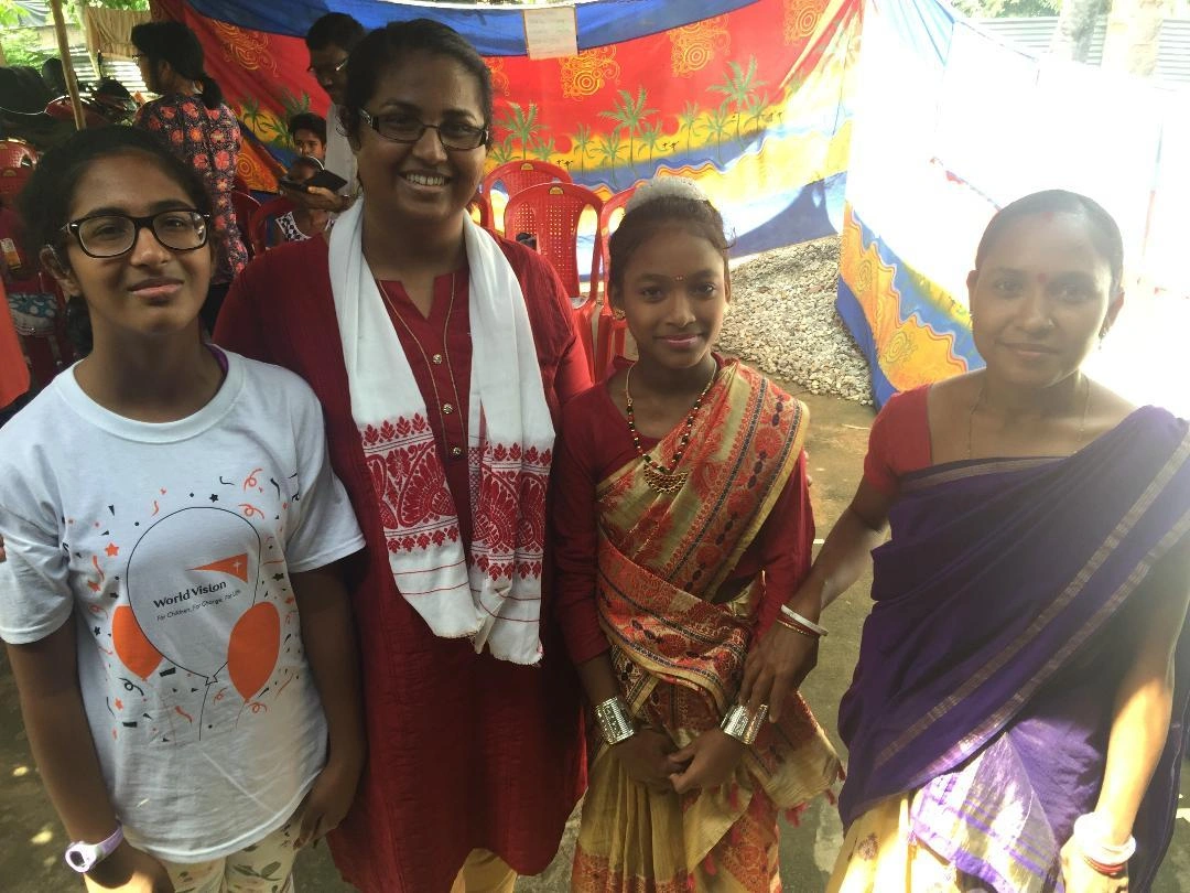 Two adolescent girls and two middle-aged women smile together.