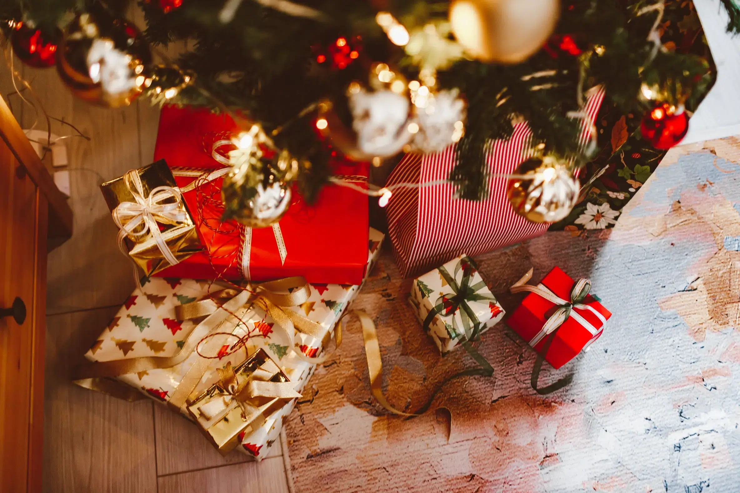 Top-down view of colourfully wrapped Christmas gifts of all sizes under a Christmas tree