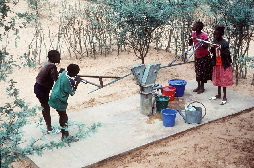 our adolescents work together to pump water from a two-sided water distribution point.