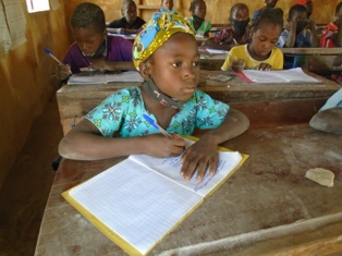 A girl sits at a desk and writes in a notebook.