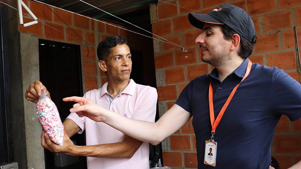 Miguel talks to World Vision Representative and holds sweets from his business in Colombia.