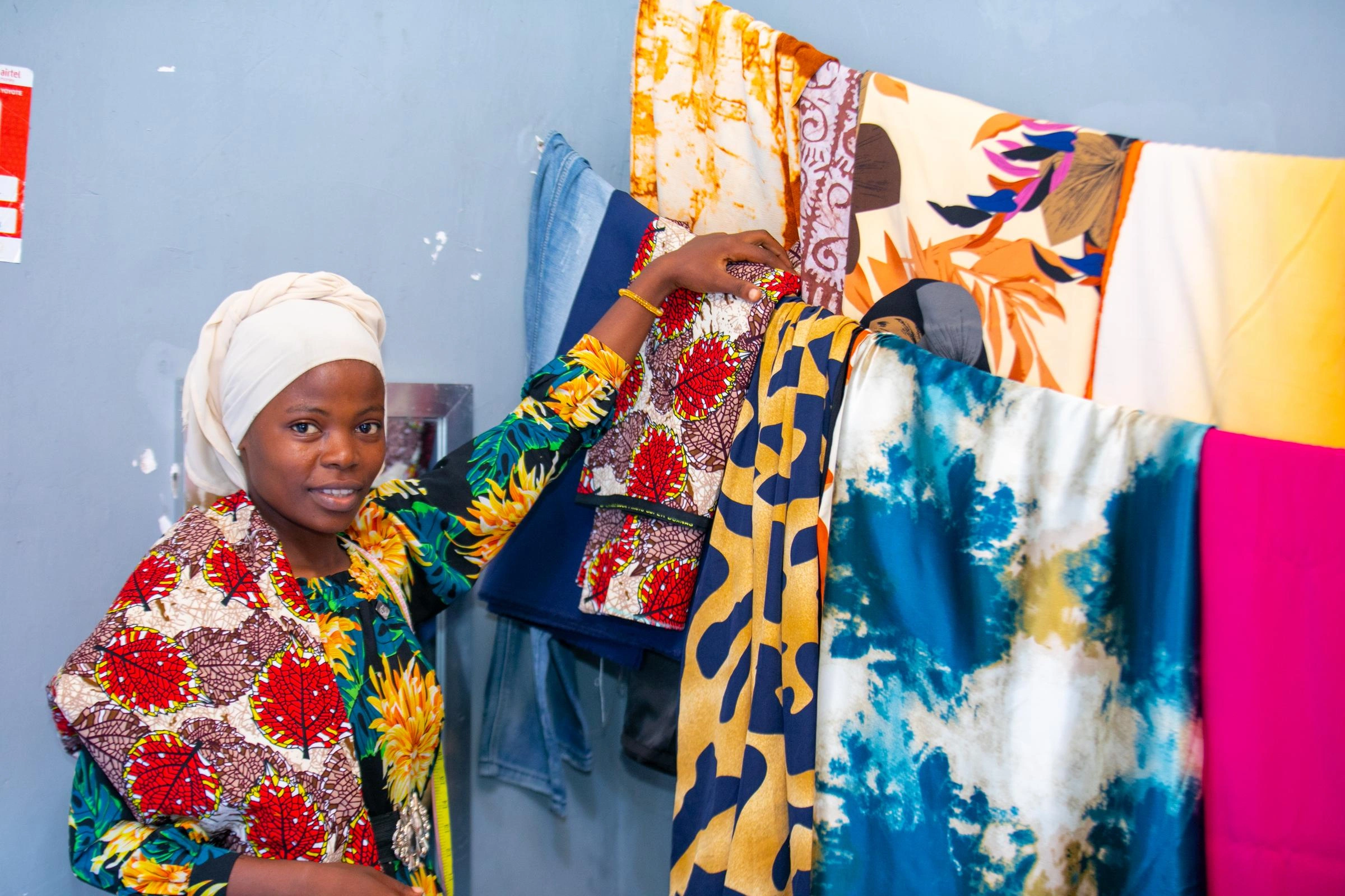 A girl stands next to a clothesline full of sewing projects.