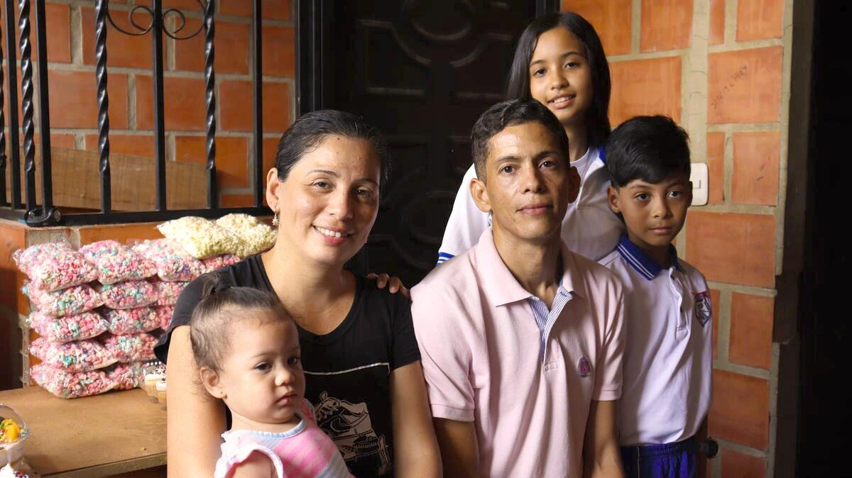 Yesleidy, Miguel and family pose for a picture in Columbia with the sweets from their business in the back.