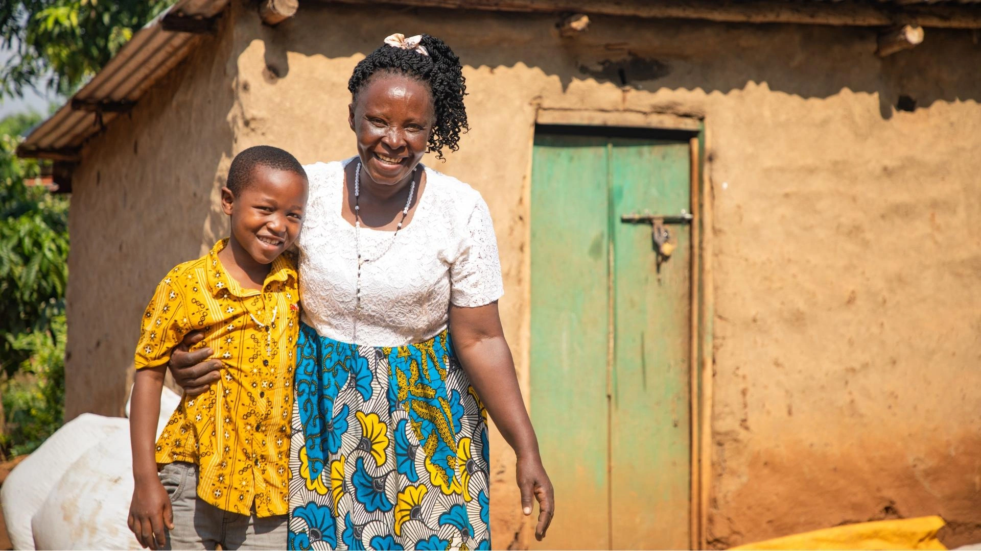Javira and his grandmother Dinah smile outside their home, with her arm around him.