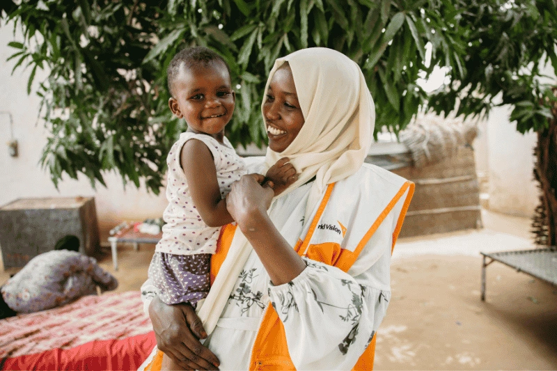 World Vision staff member holds a young child.
