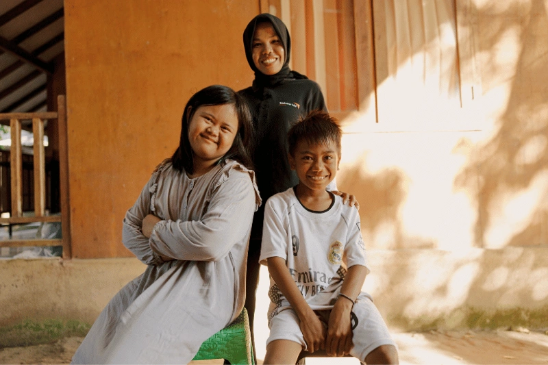 3 children smile together for a photo.