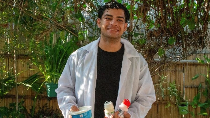 Alfonso, a young entrepreneur in Ecuador, holds three packaged dairy products from his business, France Lácteos.