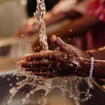 Child washes their hands, over a sink, under a running tap.