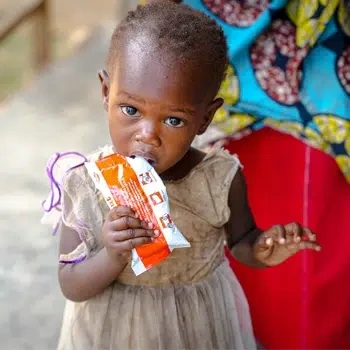 A young girl holds an opened package of ready to use therapeutic food.