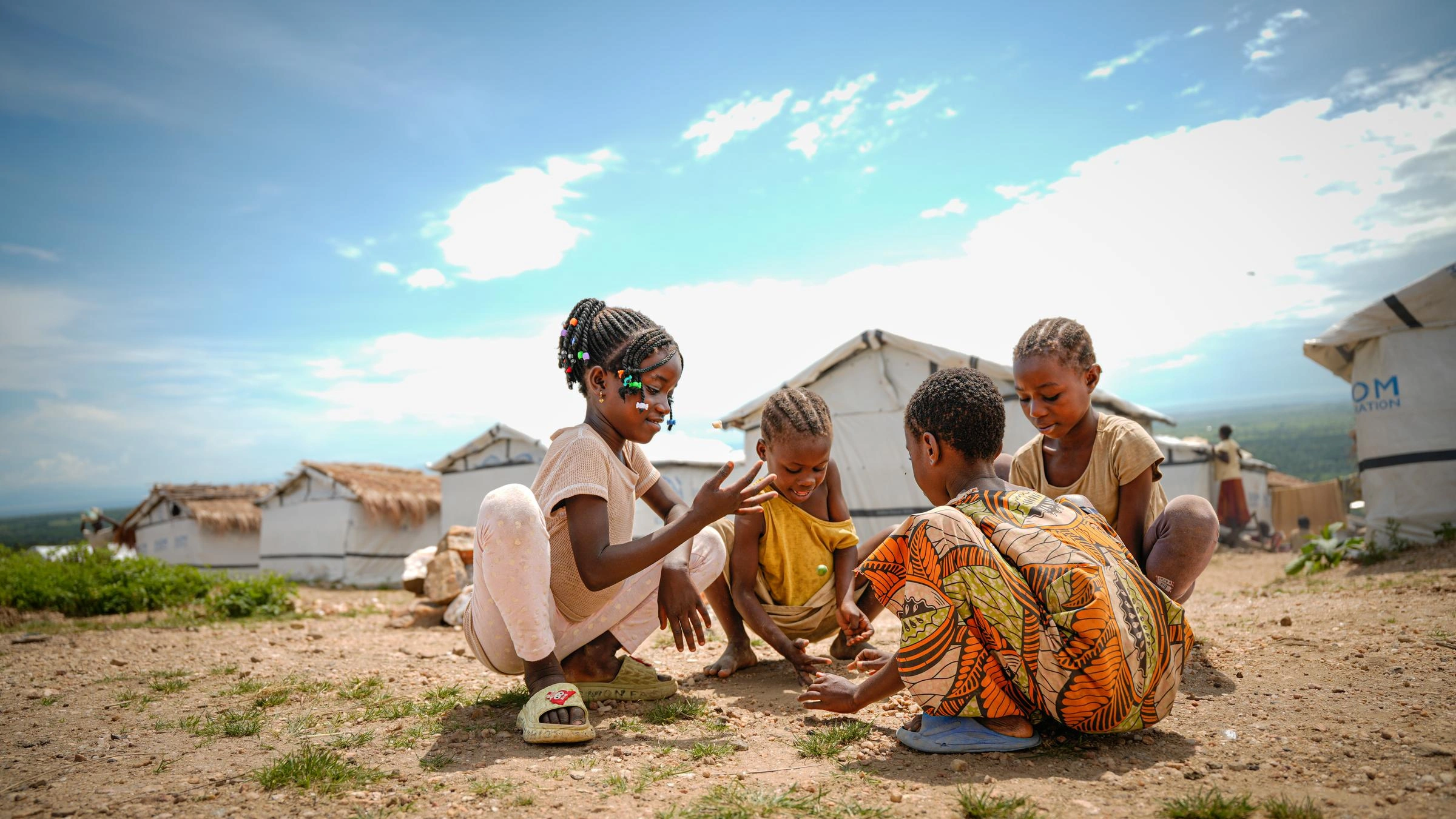 Four children play in the dirt.